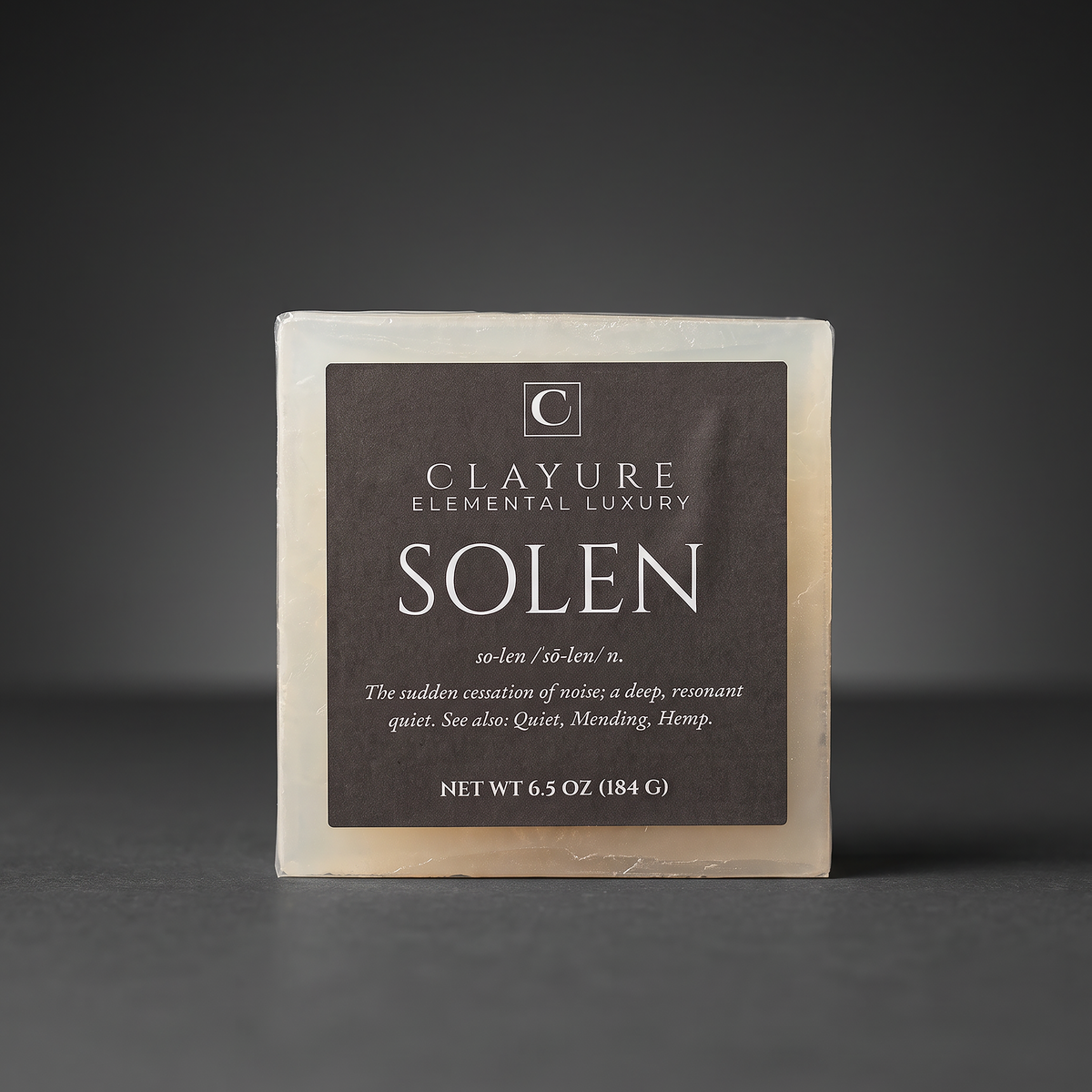 A square bar of Clayure Hemp soap named 'Solen' on a dark gray background. The soap has a dark brown label with white text and a light beige soap body visible around the edges.