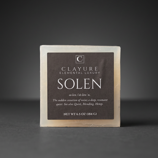 A square bar of Clayure Hemp soap named 'Solen' on a dark gray background. The soap has a dark brown label with white text and a light beige soap body visible around the edges.